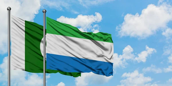 Pákistán a Sierra Leone vlají ve větru proti bíle zatažené modré obloze. Diplomacie, mezinárodní vztahy. — Stock fotografie