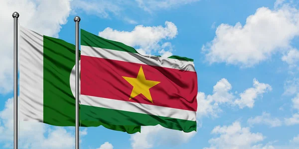 Bandera de Pakistán y Surinam ondeando en el viento contra el cielo azul nublado blanco juntos. Concepto diplomático, relaciones internacionales . — Foto de Stock