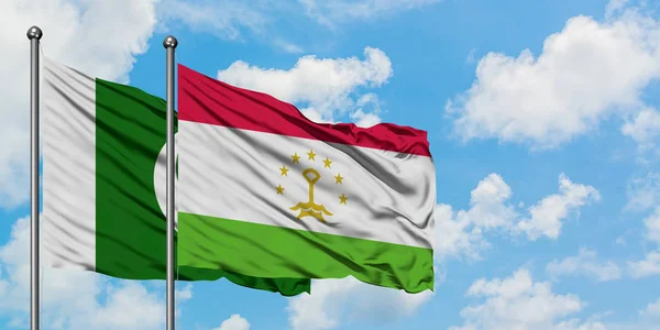 Bandera de Pakistán y Tayikistán ondeando en el viento contra el cielo azul nublado blanco juntos. Concepto diplomático, relaciones internacionales . — Foto de Stock