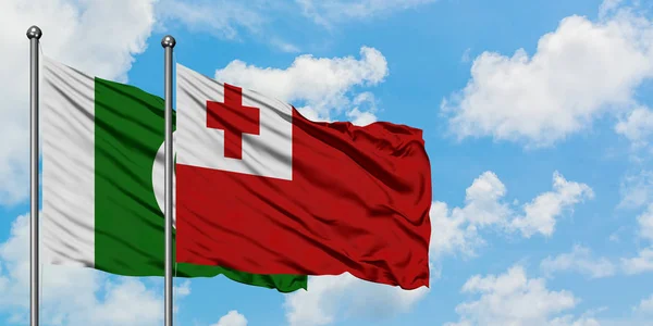 Bandera de Pakistán y Tonga ondeando en el viento contra el cielo azul nublado blanco juntos. Concepto diplomático, relaciones internacionales . — Foto de Stock