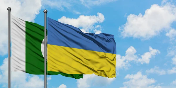 Pákistán a ukrajinská vlajka mávali ve větru proti bíle zatažené modré obloze. Diplomacie, mezinárodní vztahy. — Stock fotografie