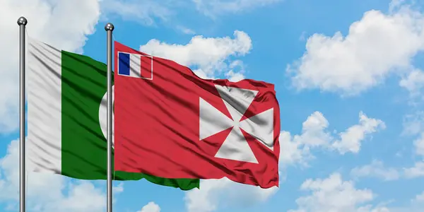 Pakistán y Wallis Y la bandera de Futuna ondeando en el viento contra el cielo azul nublado blanco juntos. Concepto diplomático, relaciones internacionales . — Foto de Stock