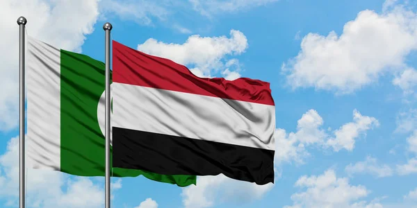 Bandera de Pakistán y Yemen ondeando en el viento contra el cielo azul nublado blanco juntos. Concepto diplomático, relaciones internacionales . — Foto de Stock