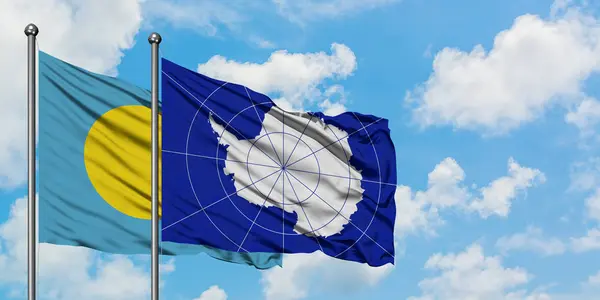 Bandera de Palaos y Antártida ondeando en el viento contra el cielo azul nublado blanco juntos. Concepto diplomático, relaciones internacionales . — Foto de Stock