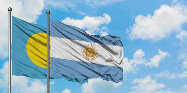 Palau e a bandeira da Argentina agitando no vento contra o céu azul nublado branco juntos. Conceito de diplomacia, relações internacionais . — Fotografia de Stock