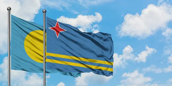 Palau a Arubova vlajka mávali ve větru proti bíle zatažené modré obloze. Diplomacie, mezinárodní vztahy. — Stock fotografie