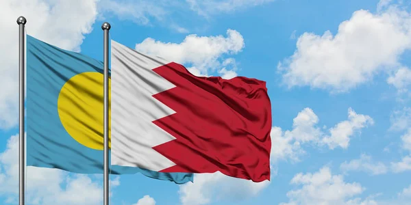 Bandera de Palaos y Bahréin ondeando en el viento contra el cielo azul nublado blanco juntos. Concepto diplomático, relaciones internacionales . — Foto de Stock