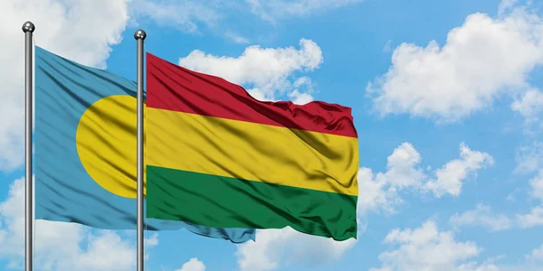 Bandera de Palaos y Bolivia ondeando en el viento contra el cielo azul nublado blanco juntos. Concepto diplomático, relaciones internacionales . — Foto de Stock