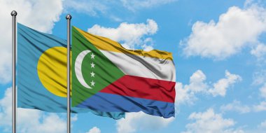 Palau ve Komorbayrağı birlikte beyaz bulutlu mavi gökyüzüne karşı rüzgarda sallayarak. Diplomasi kavramı, uluslararası ilişkiler.