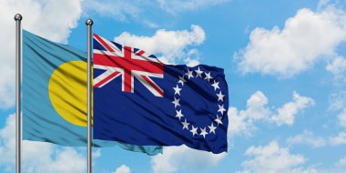 Palau ve Cook Adaları bayrak birlikte beyaz bulutlu mavi gökyüzüne karşı rüzgarda sallayarak. Diplomasi kavramı, uluslararası ilişkiler.