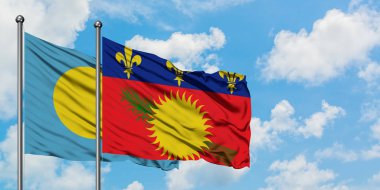 Palau ve Guadeloupe bayrağı birlikte beyaz bulutlu mavi gökyüzüne karşı rüzgarda sallayarak. Diplomasi kavramı, uluslararası ilişkiler.
