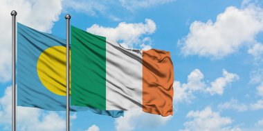 Palau ve İrlanda bayrağı birlikte beyaz bulutlu mavi gökyüzüne karşı rüzgarda sallayarak. Diplomasi kavramı, uluslararası ilişkiler.