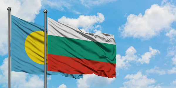 Bandera de Palaos y Bulgaria ondeando en el viento contra el cielo azul nublado blanco juntos. Concepto diplomático, relaciones internacionales . — Foto de Stock