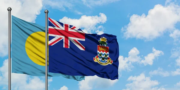 帕劳和开曼群岛国旗在风中飘扬，与白云蓝天相联。外交概念、国际关系. — 图库照片