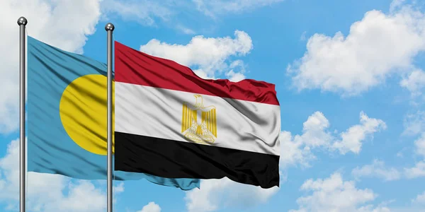 Bandera de Palaos y Egipto ondeando en el viento contra el cielo azul nublado blanco juntos. Concepto diplomático, relaciones internacionales . — Foto de Stock