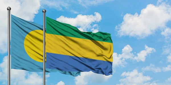 Palaos et le Gabon drapeau agitant dans le vent contre ciel bleu nuageux blanc ensemble. Concept de diplomatie, relations internationales . — Photo