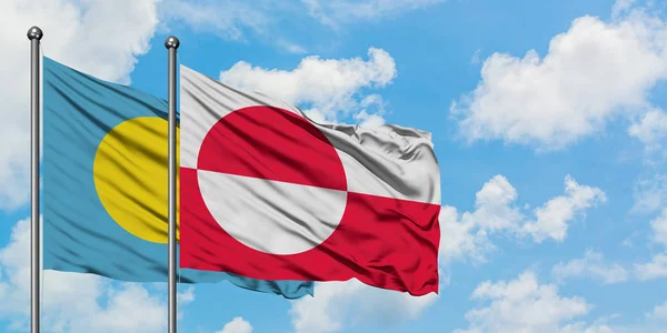 Bandera de Palaos y Groenlandia ondeando en el viento contra el cielo azul nublado blanco juntos. Concepto diplomático, relaciones internacionales . — Foto de Stock