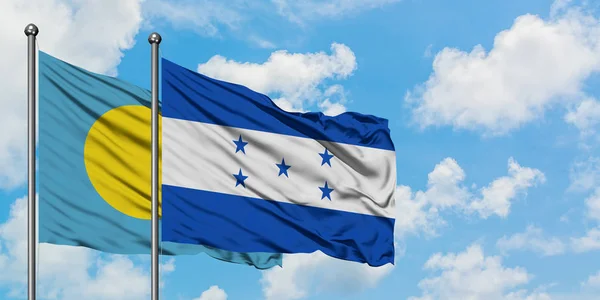 Το Παλάου και η Ονδούρα κυματίζει στον άνεμο ενάντια στον λευκό νεφελώδες γαλάζιο ουρανό μαζί. Φιλοσοφία της διπλωματίας, διεθνείς σχέσεις. — Φωτογραφία Αρχείου