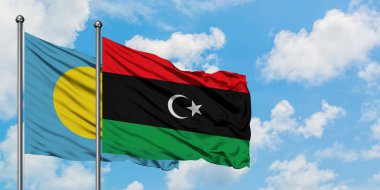 Palau ve Libya bayrağı birlikte beyaz bulutlu mavi gökyüzüne karşı rüzgarda sallayarak. Diplomasi kavramı, uluslararası ilişkiler.