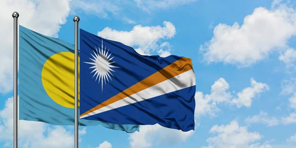 Drapeau des îles Palau et Marshall agitant dans le vent contre ciel bleu nuageux blanc ensemble. Concept de diplomatie, relations internationales . — Photo