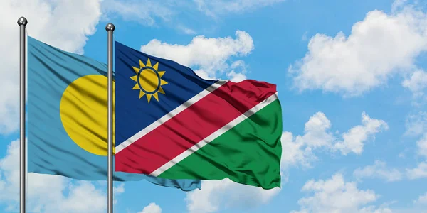 Palau és Namíbia zászló integetett a szél ellen, fehér felhős kék ég együtt. Diplomáciai koncepció, nemzetközi kapcsolatok. — Stock Fotó