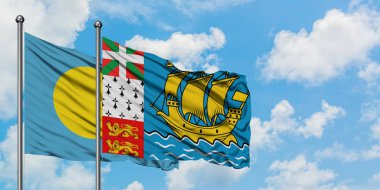 Palau ve Saint Pierre ve Miquelon bayrağı birlikte beyaz bulutlu mavi gökyüzüne karşı rüzgarda sallayarak. Diplomasi kavramı, uluslararası ilişkiler.