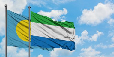 Palau ve Sierra Leone bayrağı birlikte beyaz bulutlu mavi gökyüzüne karşı rüzgarda sallayarak. Diplomasi kavramı, uluslararası ilişkiler.