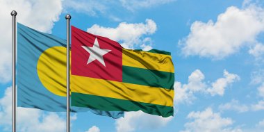 Palau ve Togo bayrağı birlikte beyaz bulutlu mavi gökyüzüne karşı rüzgarda sallayarak. Diplomasi kavramı, uluslararası ilişkiler.