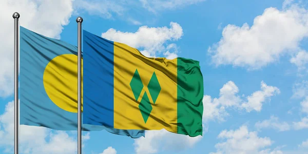 Palau i Saint Vincent i Grenadyny flagi machając w wiatr przed białym zachmurzone błękitne niebo razem. Koncepcja dyplomacji, stosunki międzynarodowe. — Zdjęcie stockowe