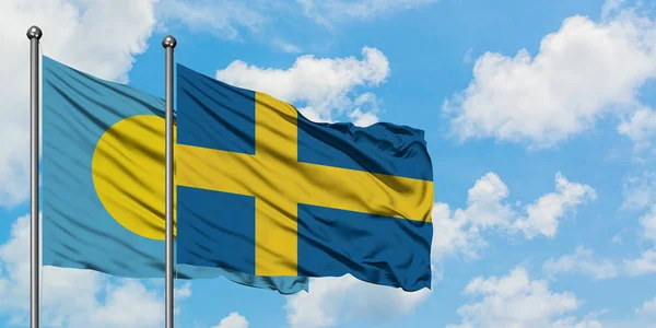 Палау и шведский флаг, размахивающие ветром против белого облачно-голубого неба вместе. Концепция дипломатии, международные отношения . — стоковое фото