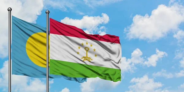 Bandera de Palaos y Tayikistán ondeando en el viento contra el cielo azul nublado blanco juntos. Concepto diplomático, relaciones internacionales . — Foto de Stock