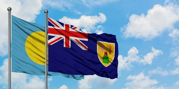 Bandera de Palaos y Islas Turcas y Caicos ondeando en el viento contra el cielo azul nublado blanco juntos. Concepto diplomático, relaciones internacionales . — Foto de Stock