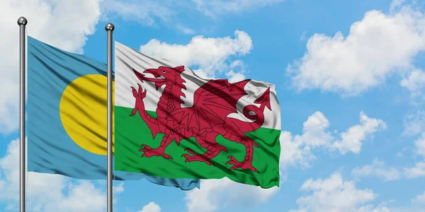 Bandera de Palaos y Gales ondeando en el viento contra el cielo azul nublado blanco juntos. Concepto diplomático, relaciones internacionales . — Foto de Stock