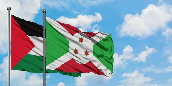 Bandera de Palestina y Burundi ondeando en el viento contra el cielo azul nublado blanco juntos. Concepto diplomático, relaciones internacionales . — Foto de Stock