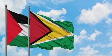 Filistin ve Guyana bayrağı birlikte beyaz bulutlu mavi gökyüzüne karşı rüzgarda sallayarak. Diplomasi kavramı, uluslararası ilişkiler.