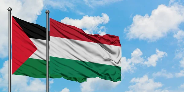 Bandera de Palestina y Hungría ondeando en el viento contra el cielo azul nublado blanco juntos. Concepto diplomático, relaciones internacionales . — Foto de Stock