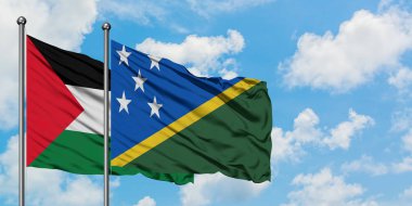 Filistin ve Solomon Adaları bayrağı birlikte beyaz bulutlu mavi gökyüzüne karşı rüzgarda sallayarak. Diplomasi kavramı, uluslararası ilişkiler.