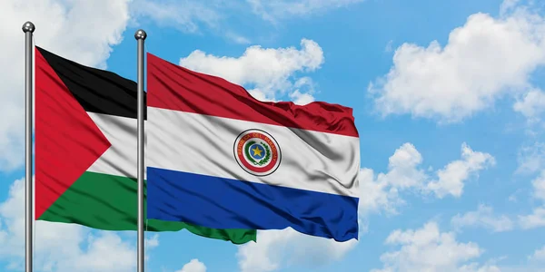 Bandera de Palestina y Paraguay ondeando en el viento contra el cielo azul nublado blanco juntos. Concepto diplomático, relaciones internacionales . — Foto de Stock