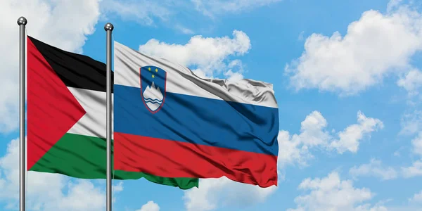 Palestine and Slovenia flag waving in the wind against white cloudy blue sky together. Diplomacy concept, international relations.