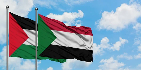 Bandera de Palestina y Sudán ondeando en el viento contra el cielo azul nublado blanco juntos. Concepto diplomático, relaciones internacionales . — Foto de Stock