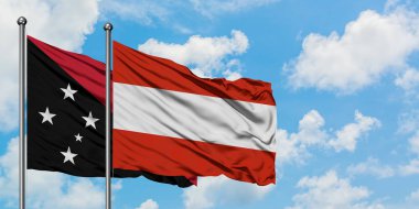 Papua Yeni Gine ve Avusturya bayrağı birlikte beyaz bulutlu mavi gökyüzüne karşı rüzgarsal sallayarak. Diplomasi kavramı, uluslararası ilişkiler.