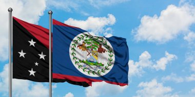 Papua Yeni Gine ve Belize bayrağı birlikte beyaz bulutlu mavi gökyüzüne karşı rüzgarda sallayarak. Diplomasi kavramı, uluslararası ilişkiler.