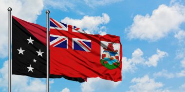 Papua Yeni Gine ve Bermuda bayrağı birlikte beyaz bulutlu mavi gökyüzüne karşı rüzgarda sallayarak. Diplomasi kavramı, uluslararası ilişkiler.