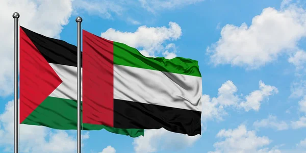 Bandera de Palestina y Emiratos Árabes Unidos ondeando en el viento contra el cielo azul nublado blanco juntos. Concepto diplomático, relaciones internacionales . — Foto de Stock