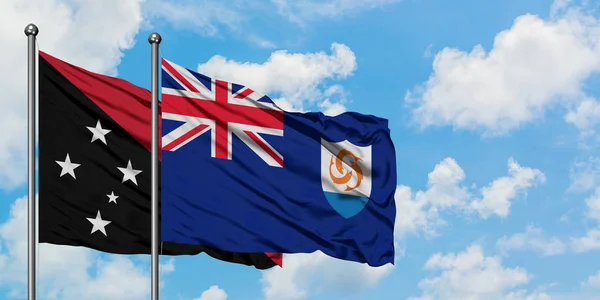 Papouasie-Nouvelle-Guinée et drapeau d'Anguilla agitant dans le vent contre ciel bleu nuageux blanc ensemble. Concept de diplomatie, relations internationales . — Photo