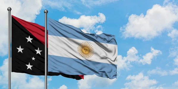 Bandera de Papúa Nueva Guinea y Argentina ondeando en el viento contra el cielo azul nublado blanco juntos. Concepto diplomático, relaciones internacionales . — Foto de Stock