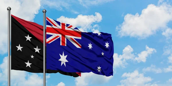 Papua Neuguinea und Australien schwenken gemeinsam die Flagge im Wind vor dem wolkenverhangenen blauen Himmel. Diplomatie-Konzept, internationale Beziehungen. — Stockfoto
