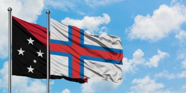 Papua Yeni Gine ve Faroe Adaları bayrağı birlikte beyaz bulutlu mavi gökyüzüne karşı rüzgarda sallayarak. Diplomasi kavramı, uluslararası ilişkiler.