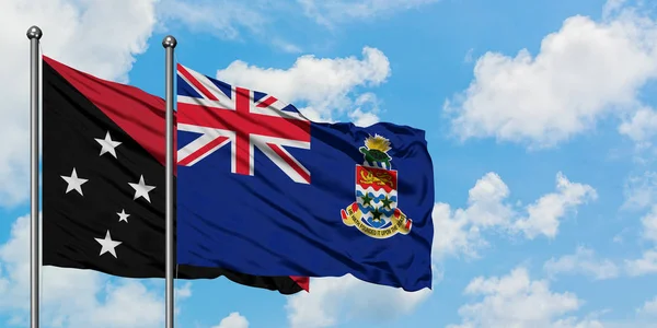 巴布亚新几内亚和开曼群岛国旗在风中飘扬，与白云蓝天相一起。外交概念、国际关系. — 图库照片