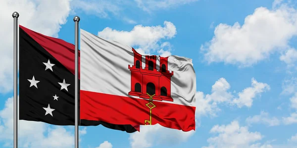 Papua New Guinea and Gibraltar flag waving in the wind against white cloudy blue sky together. Diplomacy concept, international relations. — Stock Photo, Image